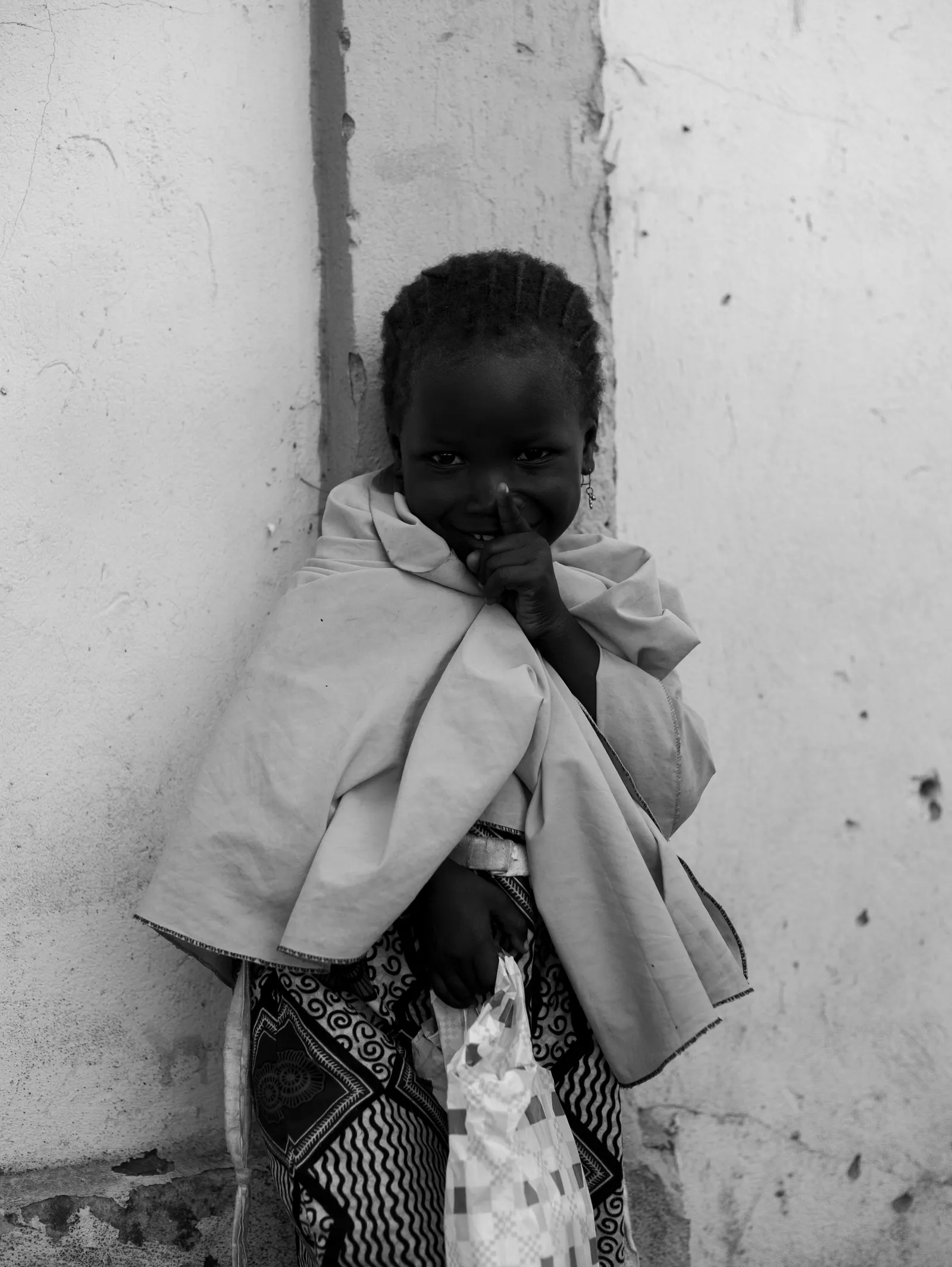 A black and white portrait of a child looking into the camera during a community visit