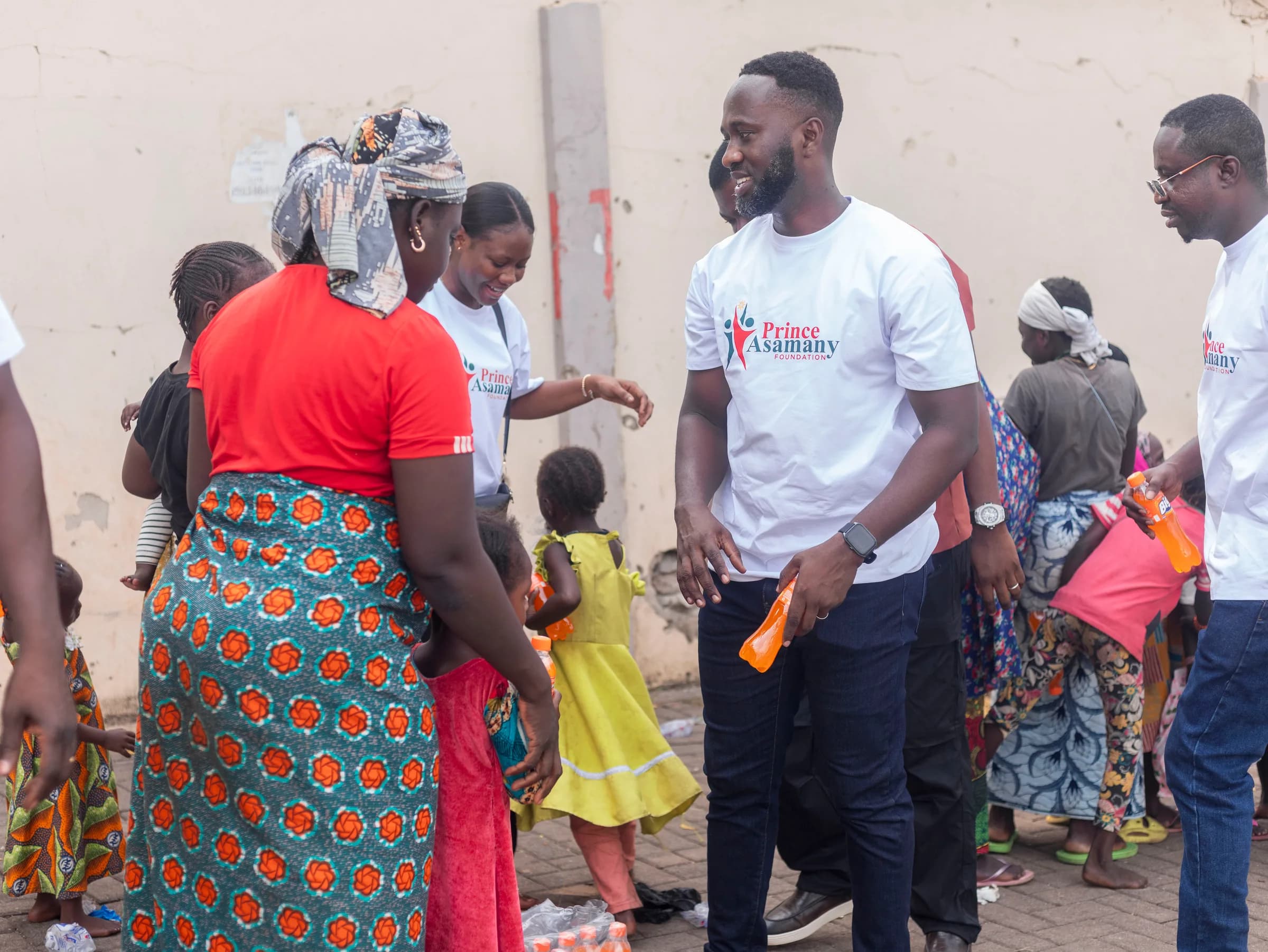 Prince Asamany speaking with a mother and child during outreach